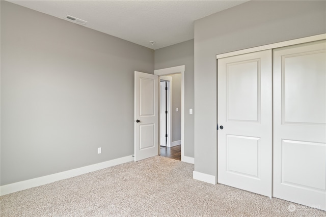 unfurnished bedroom featuring a closet, carpet floors, and a textured ceiling