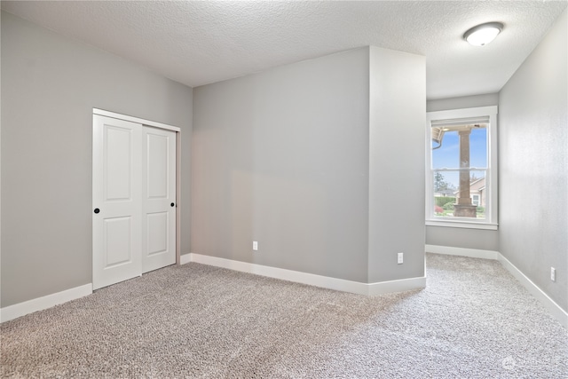 spare room featuring light colored carpet and a textured ceiling