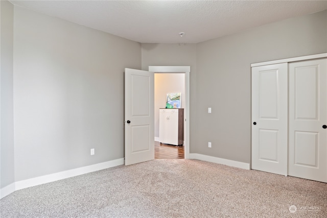 unfurnished bedroom featuring light colored carpet, a textured ceiling, and a closet