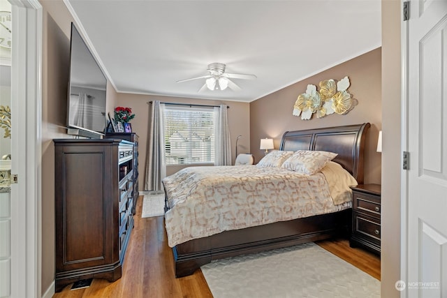 bedroom featuring a ceiling fan, ornamental molding, and wood finished floors