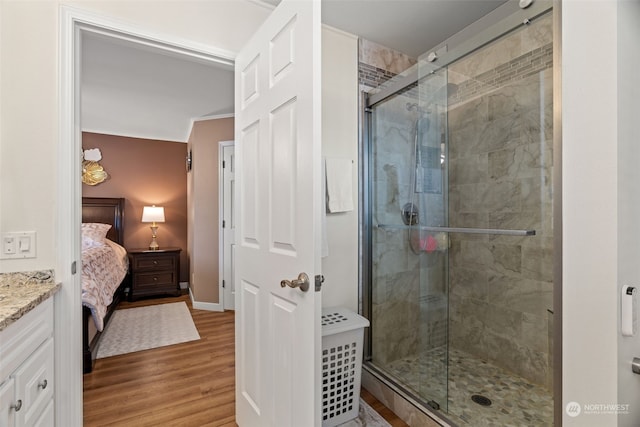 ensuite bathroom featuring baseboards, ensuite bath, wood finished floors, vanity, and a shower stall