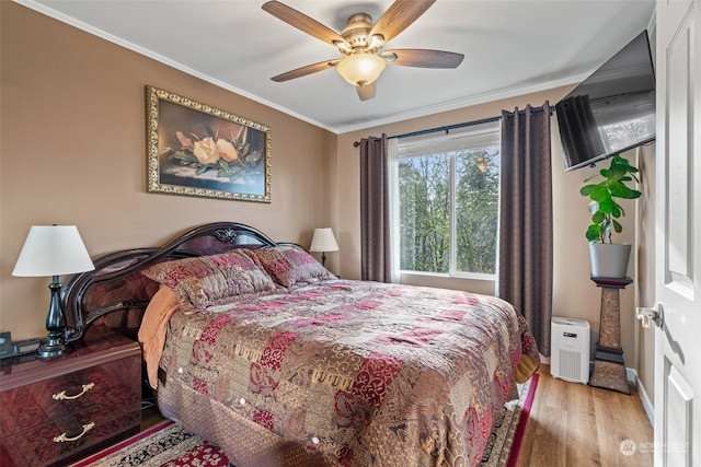 bedroom featuring a ceiling fan, crown molding, baseboards, and wood finished floors