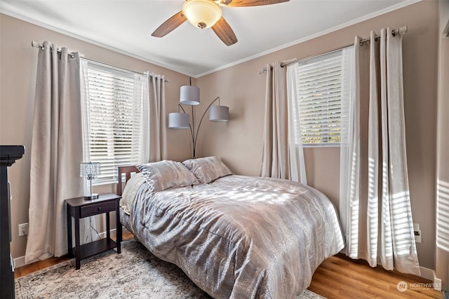 bedroom with crown molding, multiple windows, a ceiling fan, and wood finished floors