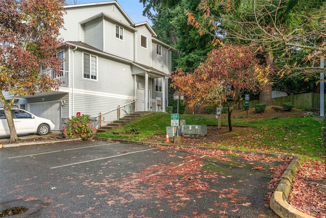 exterior space featuring a garage, uncovered parking, and fence