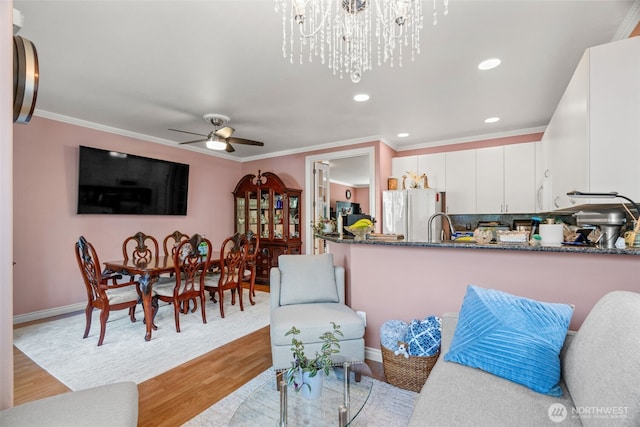 kitchen with light wood-type flooring, ornamental molding, dark stone counters, and freestanding refrigerator