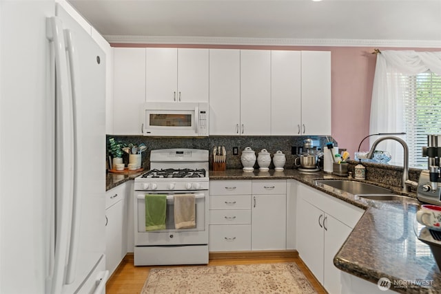 kitchen with white appliances, white cabinets, and a sink