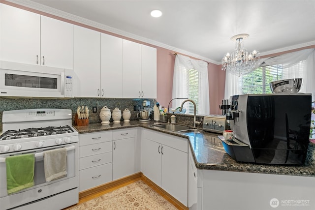 kitchen featuring white appliances, white cabinetry, a sink, and dark stone countertops