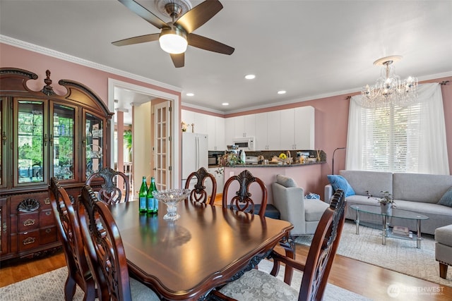 dining room with recessed lighting, ceiling fan with notable chandelier, crown molding, and wood finished floors