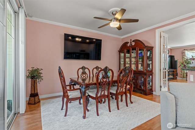 dining area with baseboards, ceiling fan, light wood finished floors, and crown molding