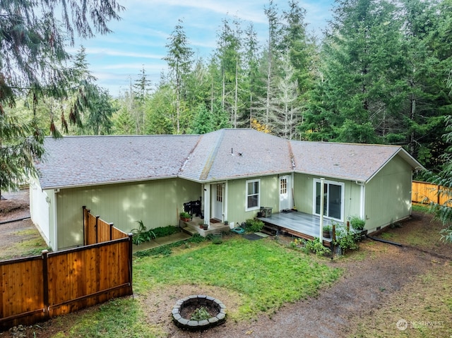 view of front facade featuring a fire pit, a wooden deck, and a front lawn