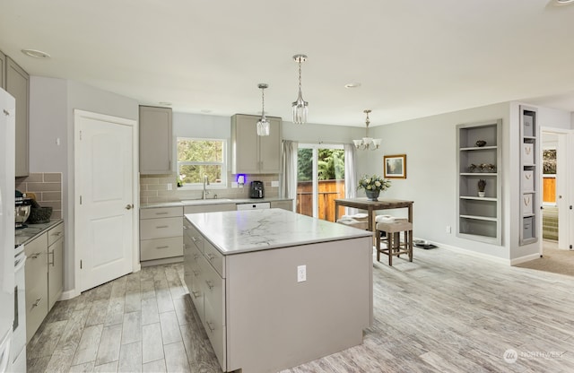 kitchen with sink, a center island, decorative light fixtures, gray cabinets, and light wood-type flooring