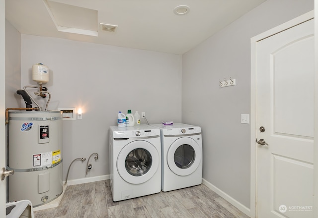 clothes washing area featuring separate washer and dryer, water heater, and light wood-type flooring