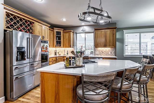 kitchen featuring tasteful backsplash, a center island, stainless steel appliances, and light wood-type flooring