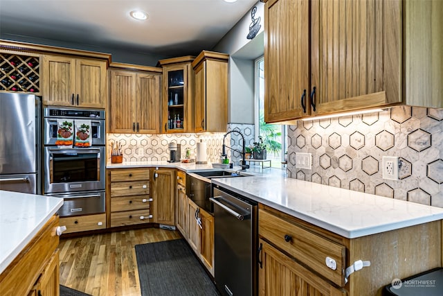 kitchen featuring light stone countertops, dark hardwood / wood-style flooring, tasteful backsplash, stainless steel appliances, and sink