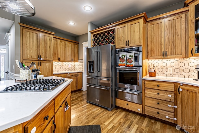 kitchen with light wood-type flooring, backsplash, and appliances with stainless steel finishes