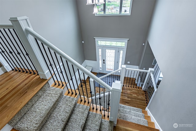 stairs with hardwood / wood-style floors and a high ceiling