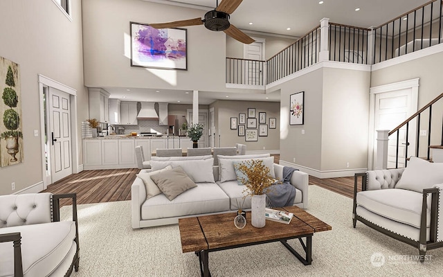 living room with ceiling fan, a towering ceiling, and light hardwood / wood-style floors