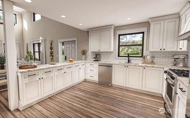 kitchen with kitchen peninsula, sink, light hardwood / wood-style floors, and appliances with stainless steel finishes