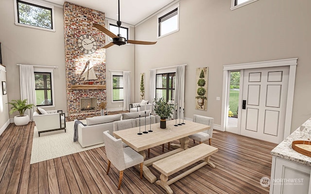 dining space featuring ceiling fan, wood-type flooring, a high ceiling, and a brick fireplace