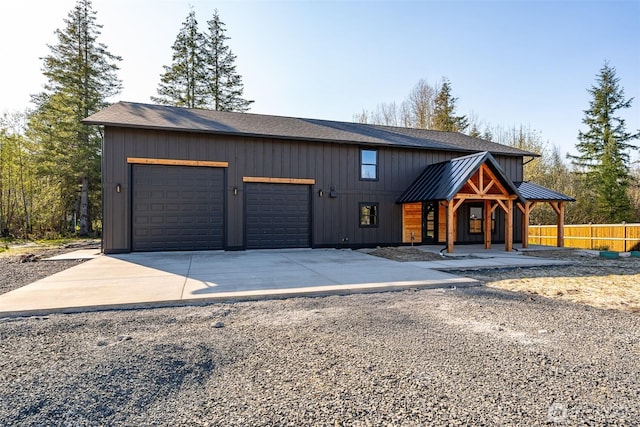 view of front facade with a standing seam roof, driveway, covered porch, fence, and a garage