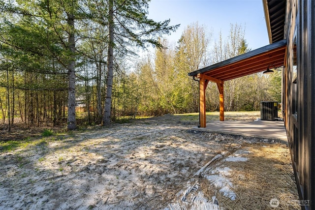 view of yard with cooling unit, a patio area, and a view of trees