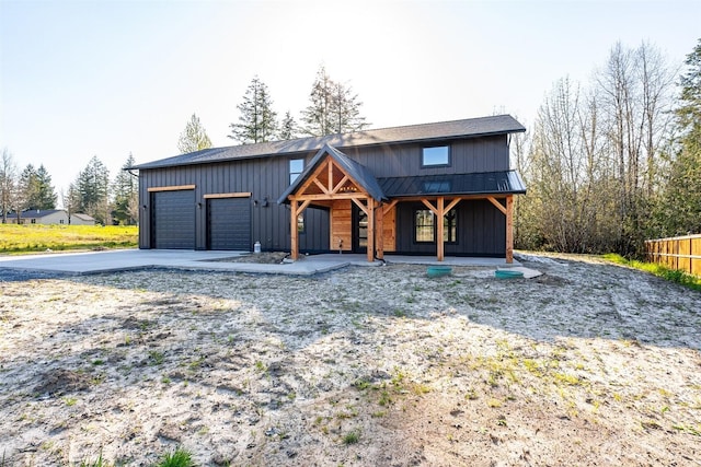 view of front of house featuring fence, a garage, a standing seam roof, a porch, and metal roof