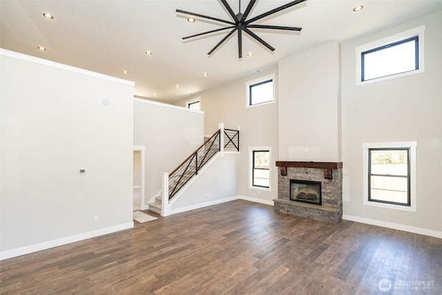 unfurnished living room featuring stairway, baseboards, and dark wood-type flooring