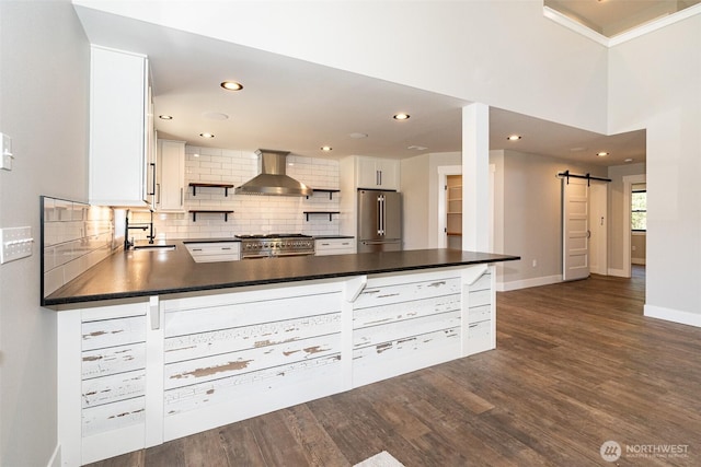 kitchen featuring wall chimney range hood, a barn door, open shelves, a sink, and high end appliances