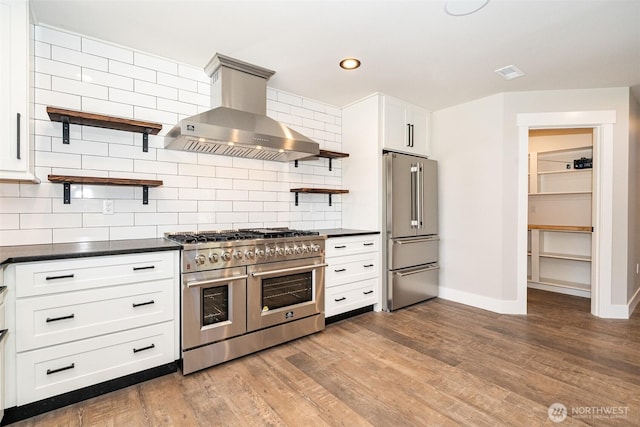 kitchen featuring open shelves, dark countertops, wall chimney range hood, baseboards, and high quality appliances