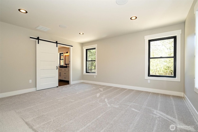 unfurnished bedroom with baseboards, recessed lighting, light colored carpet, and a barn door