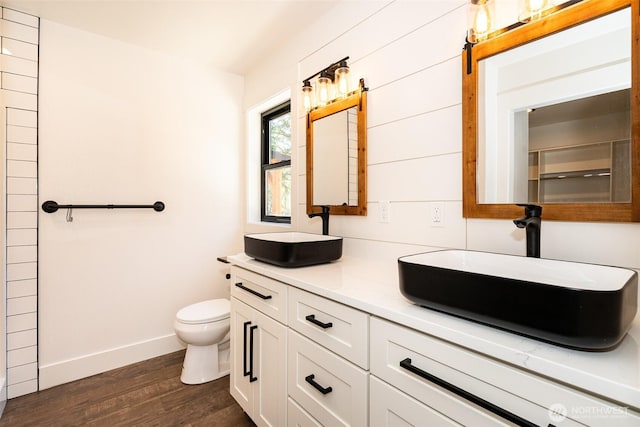 bathroom with baseboards, wood finished floors, a sink, and toilet