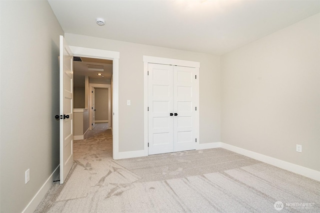 unfurnished bedroom featuring light colored carpet, baseboards, and a closet