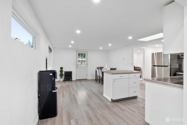 kitchen with stainless steel fridge, white cabinetry, a wealth of natural light, and a skylight