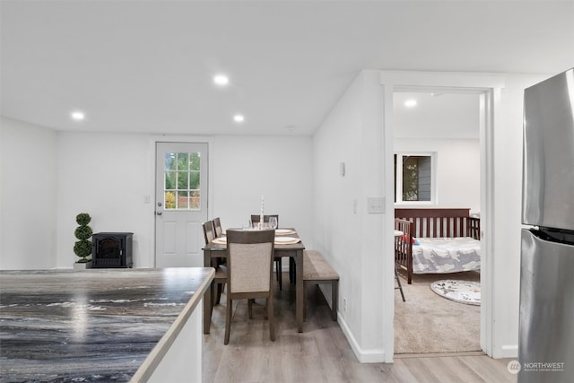 dining space with a wood stove and light hardwood / wood-style flooring