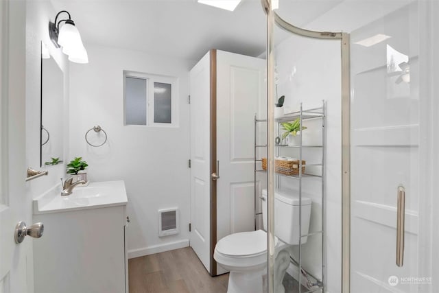 bathroom featuring heating unit, wood-type flooring, toilet, vanity, and a shower with shower door