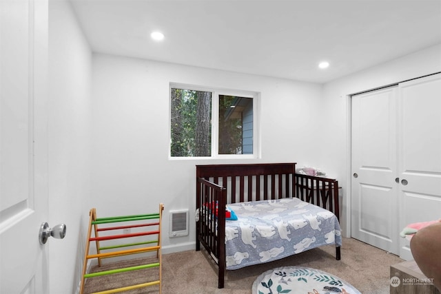 carpeted bedroom with heating unit and a closet