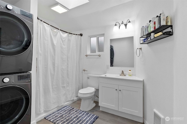 bathroom featuring a shower with curtain, vanity, stacked washer / dryer, hardwood / wood-style floors, and toilet