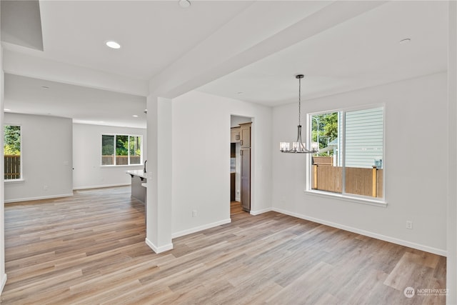 empty room featuring an inviting chandelier and light hardwood / wood-style floors