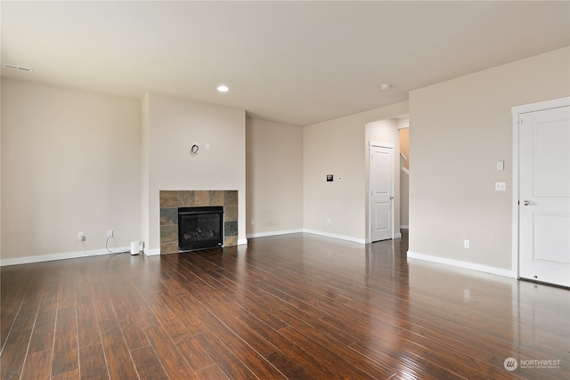 unfurnished living room with a tiled fireplace and dark hardwood / wood-style flooring