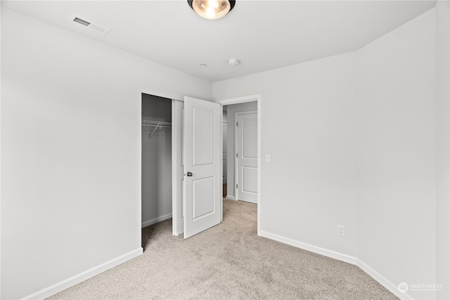 unfurnished bedroom with light carpet and a closet