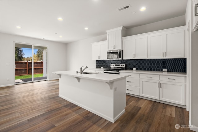 kitchen featuring stainless steel appliances, sink, white cabinets, dark hardwood / wood-style floors, and an island with sink