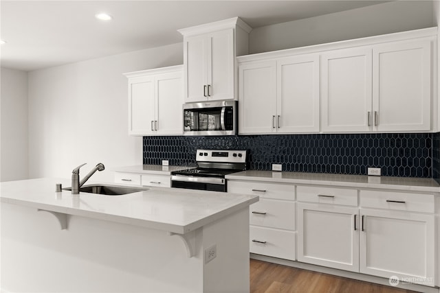 kitchen featuring a breakfast bar, decorative backsplash, stainless steel appliances, and a sink