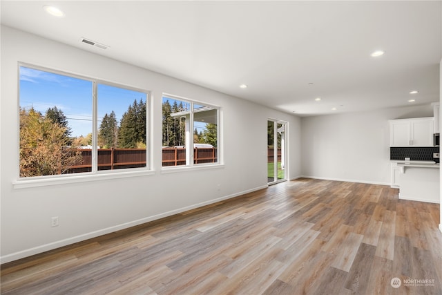 unfurnished living room with recessed lighting, visible vents, light wood finished floors, and baseboards