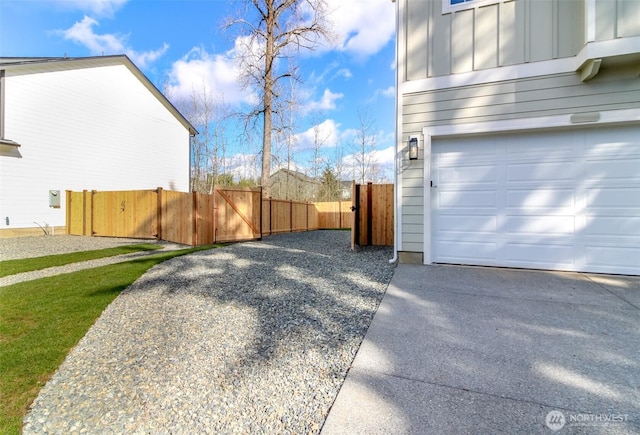 view of side of home featuring a gate, board and batten siding, an attached garage, and fence