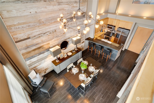 interior space with wood walls, dark hardwood / wood-style flooring, a high ceiling, and a notable chandelier