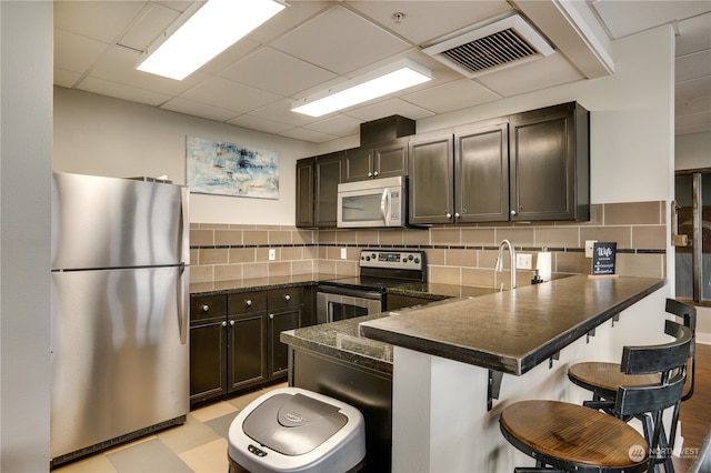 kitchen with a kitchen breakfast bar, dark brown cabinets, and stainless steel appliances