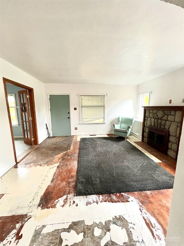 unfurnished living room featuring a stone fireplace and a textured ceiling