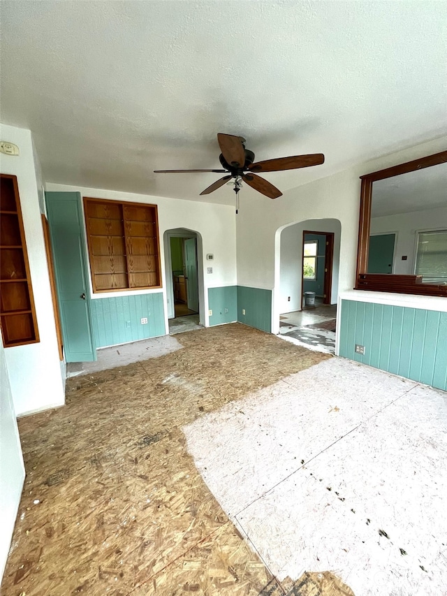 unfurnished living room with ceiling fan and a textured ceiling