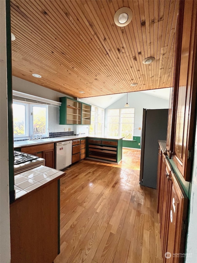 kitchen with lofted ceiling, tile counters, white dishwasher, kitchen peninsula, and light hardwood / wood-style floors