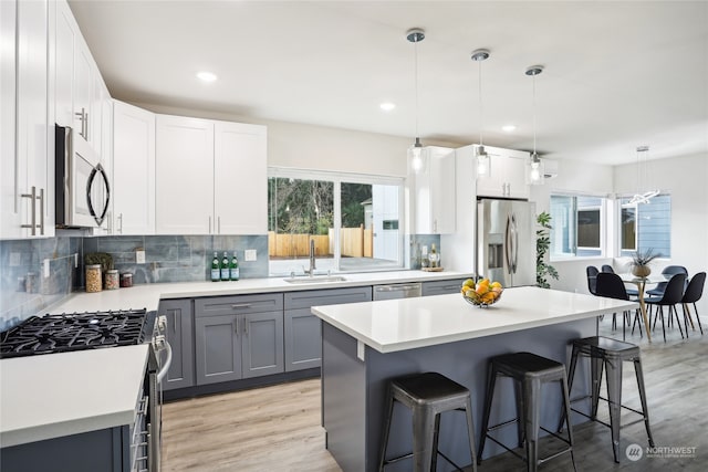 kitchen with gray cabinetry, white cabinetry, sink, stainless steel appliances, and decorative light fixtures